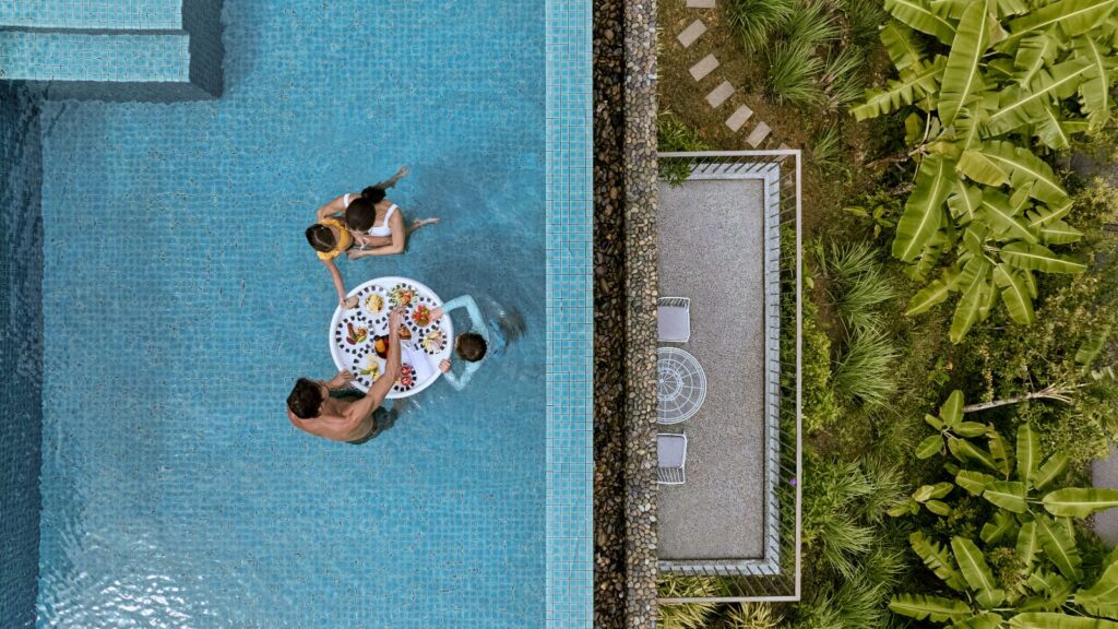 Aerial view of people in a pool with a table and food at Como Point Yamu in Thailand