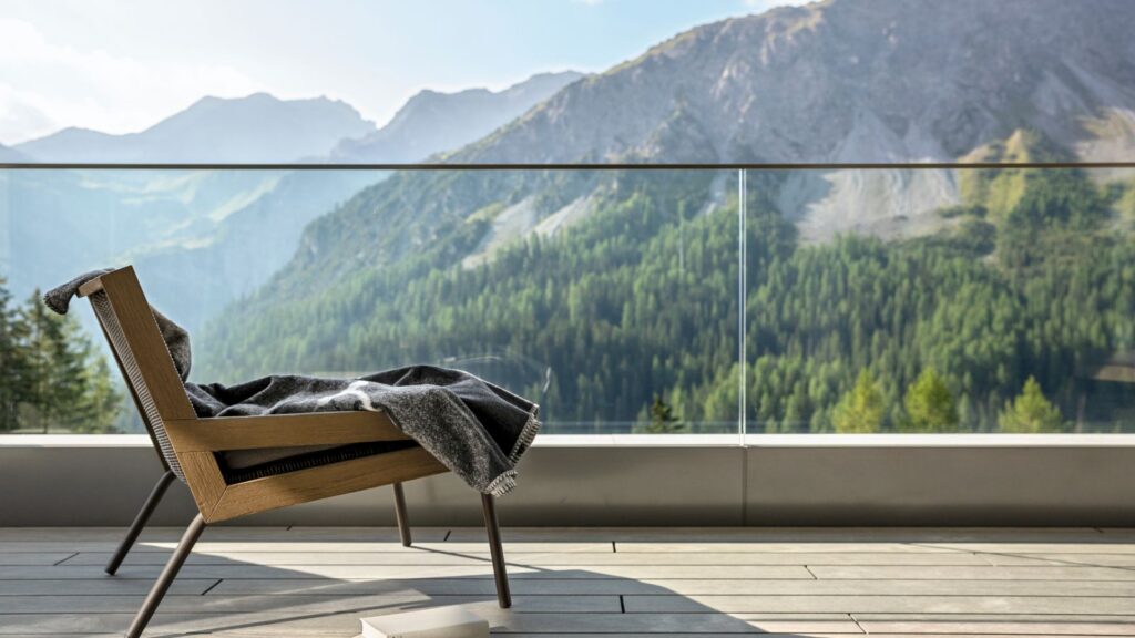 balcony with comfortable chair overlooking beautiful mountain scenery at tschuggen grand hotel