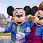 Mickey and Minnie Mouse standing in front of Sleeping Beauty Castle at Disneyland Park.