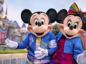 Mickey and Minnie Mouse standing in front of Sleeping Beauty Castle at Disneyland Park.