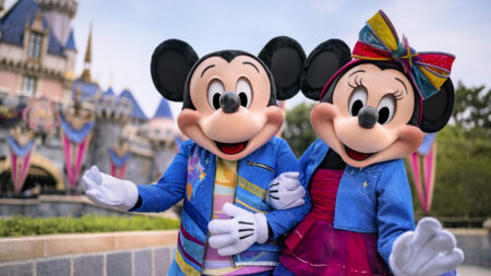 Mickey and Minnie Mouse standing in front of Sleeping Beauty Castle at Disneyland Park.