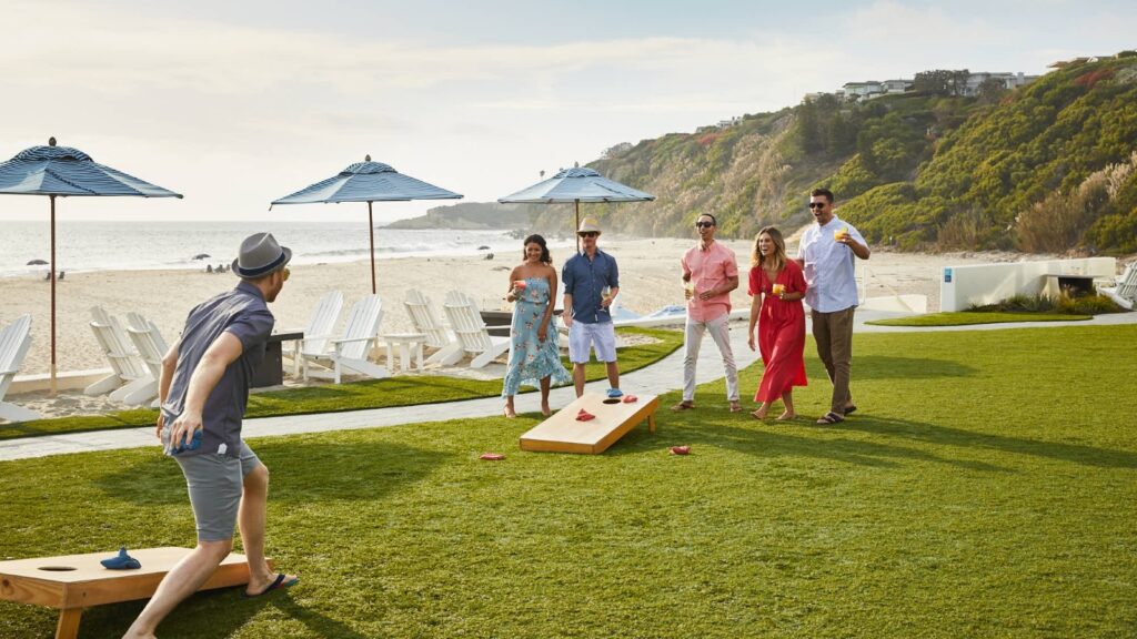 A group of people playing cornhole by the beach