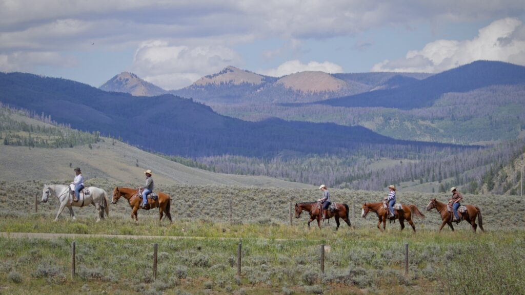 Guests on a horseback ride at C Lazy U Ranch with mountains in the distance