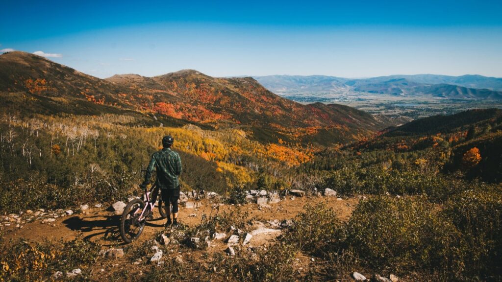 A biker on a mountain in Park City looking at the fall view