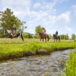 Three horseback riders by a stream at The Ranch at Rock Creek