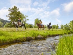Three horseback riders by a stream at The Ranch at Rock Creek