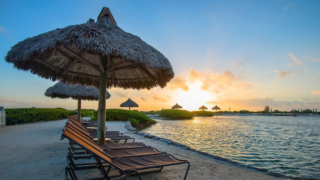 Thatch umbrellas and beach loungers at Hawks Cay Resort in Florida at sunset