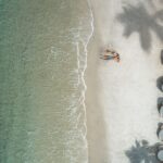 aerial view of couple on white-sand beach with aquamarine water at Sugar Beach resort in St. Lucia