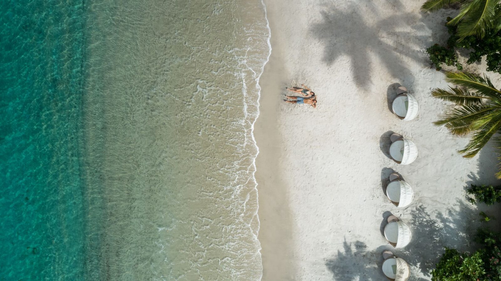 aerial view of couple on white-sand beach with aquamarine water at Sugar Beach resort in St. Lucia