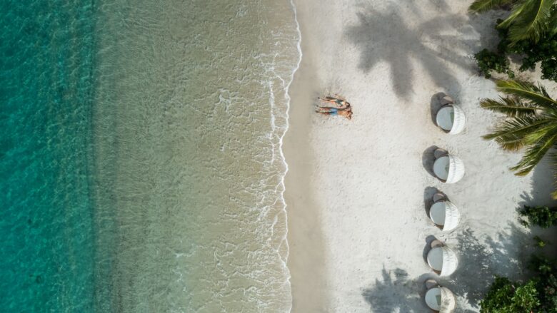 aerial view of couple on white-sand beach with aquamarine water at Sugar Beach resort in St. Lucia